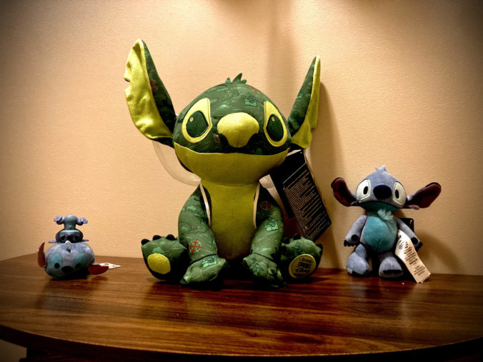 Stitch on a table surrounded by other Stitch products.